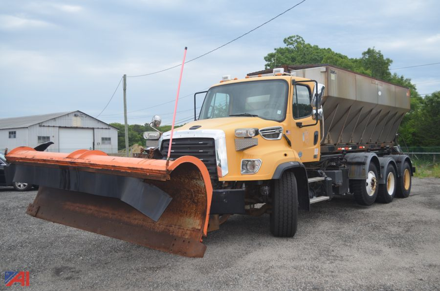 Freightliner 114SD snowplow truck with large orange plow and empty dump body in yard, front three-quarter view.