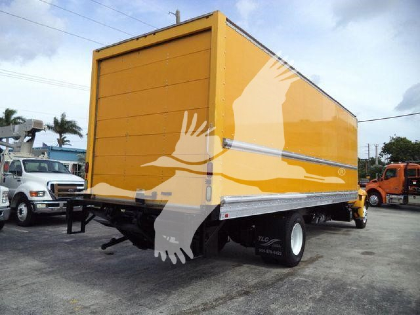 Rear/side view of an orange box truck with a yellow cargo box, single rear dual wheels, and a chrome diamond plate rail along the lower edge.