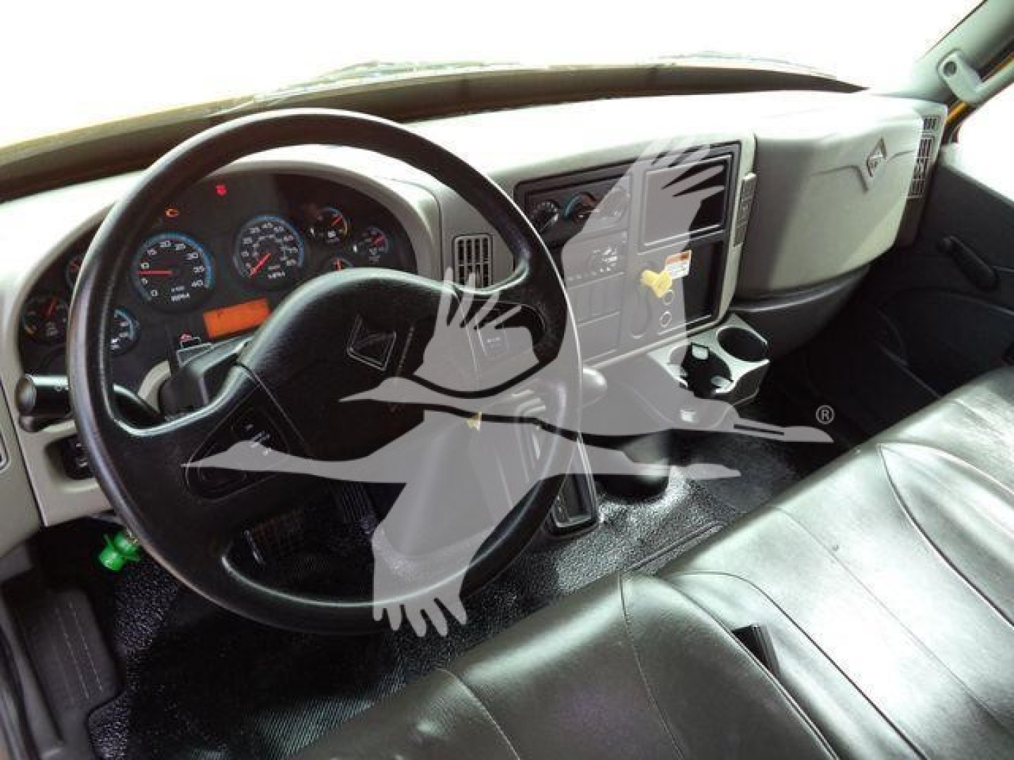 Truck interior showing steering wheel, dashboard, and center console of a 2018 International Durastar 4300 with black leather seats and a touchscreen display.
