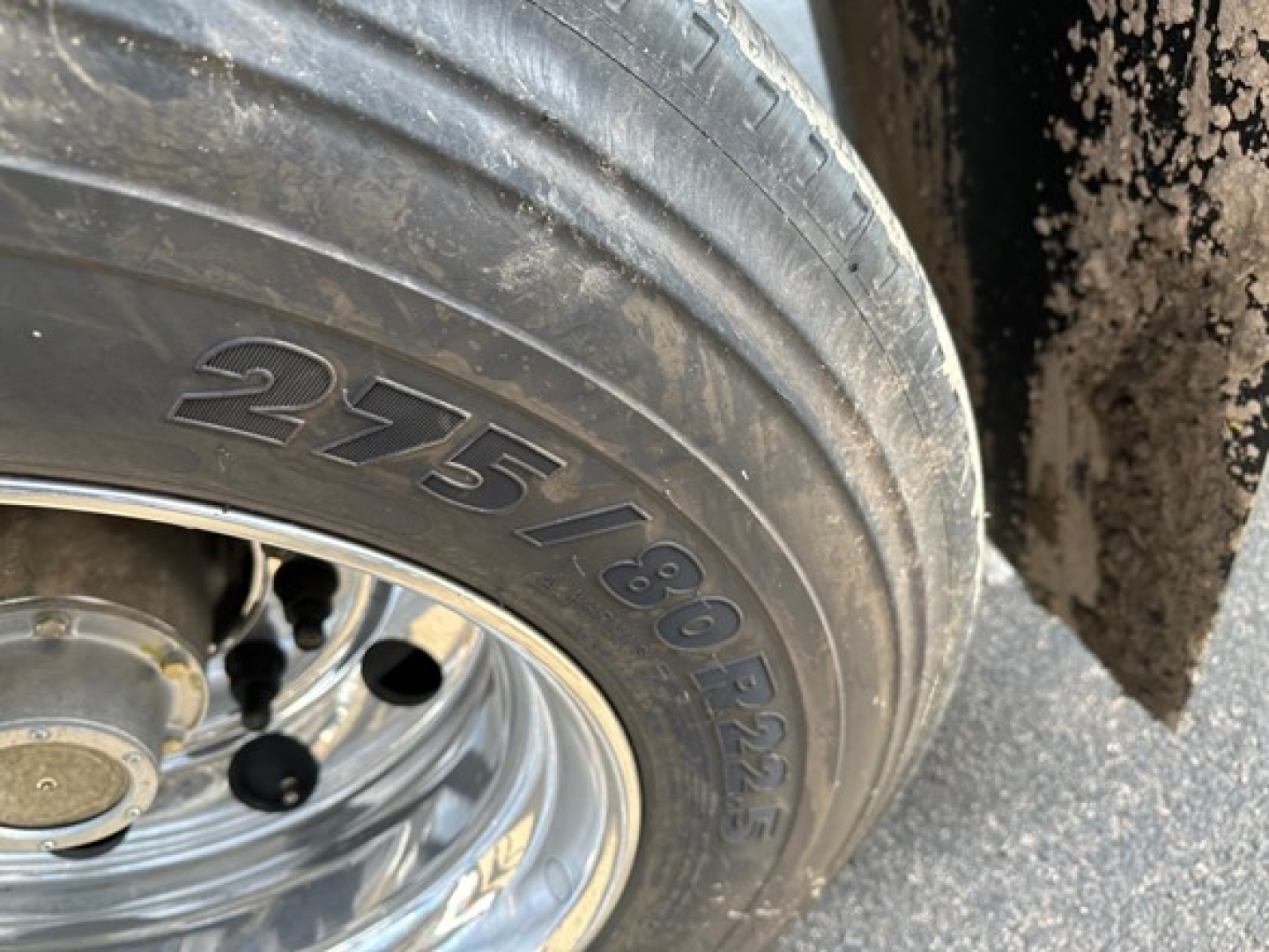 Wheel and tire sidewall with 275/80R22.5 marking on a utility trailer, reflective metal rim and hub area visible.