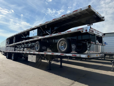 Trailer flatbed trailer with dual level loading ramp raised, Utility 4000AE logo not visible, multiple wheels, chrome rims, metal frame, reflective tape along edges.
