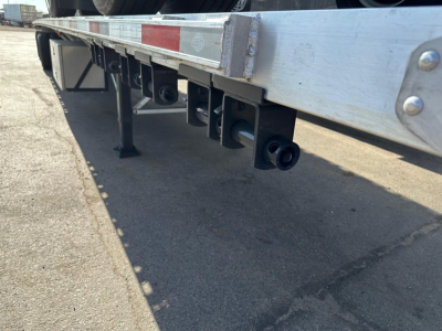 Flatbed trailer rear underside showing load lights and reinforced frame with black mounting brackets.