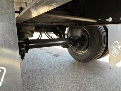 Trailer undercarriage showing axle and suspension components with a single rear dual wheel, Utility brand mudflap visible.