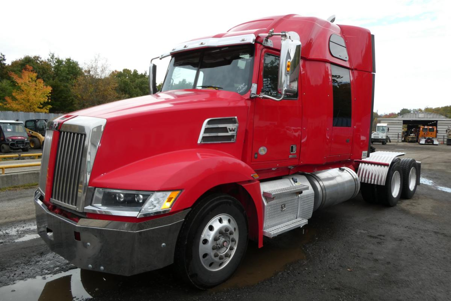 Red 2019 Western Star 5700XE conventional sleeper truck, front-left view, chrome grille, dual rear axles, fuel tanks, and cab details visible.