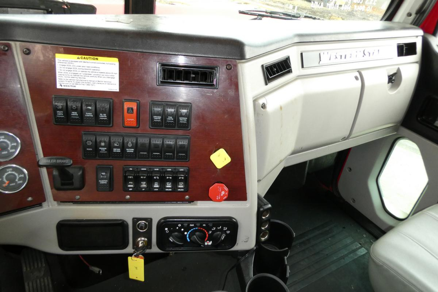 Truck cab dashboard with wood paneling showing switches, gauges, and climate controls in a 2019 Western Star 5700XE.