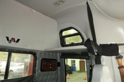 Cab interior of a Western Star 5700XE with overhead sleeper area, window, and leather quilted paneling.