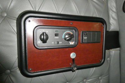 Truck cab interior control panel mounted on wood grain panel with dials and switches. Includes A/C controls, power, and two knobs.