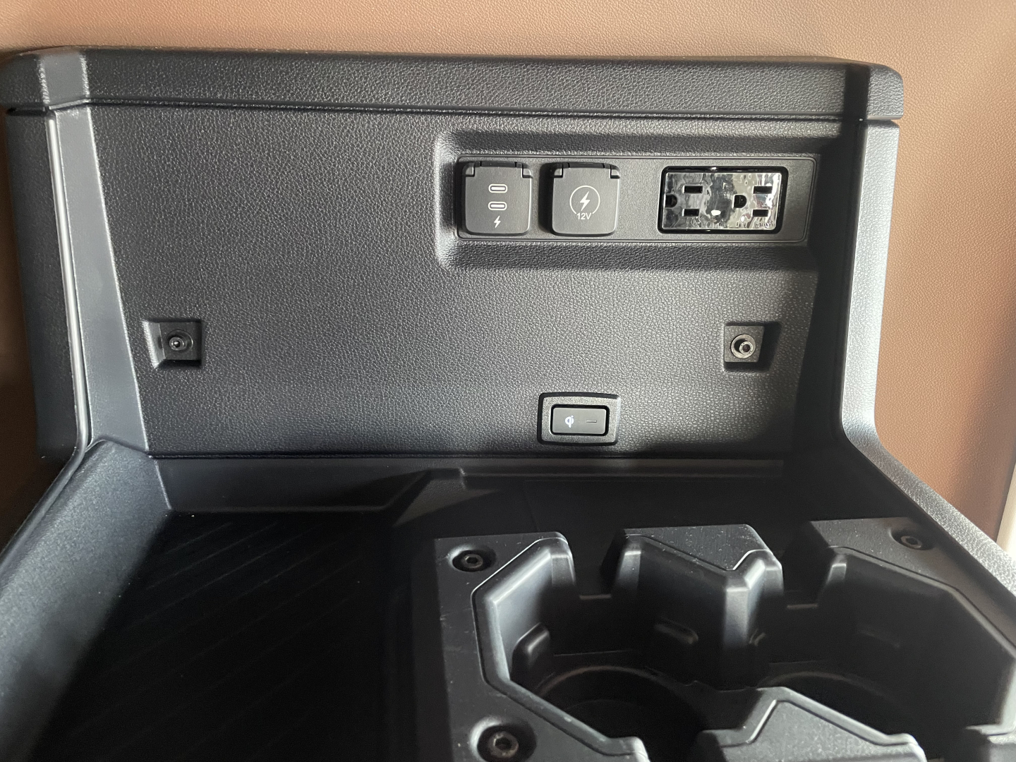 In-cab power and USB outlets panel with two USB-C/USB-A ports and auxiliary 12V socket, and center console cup holders visible.