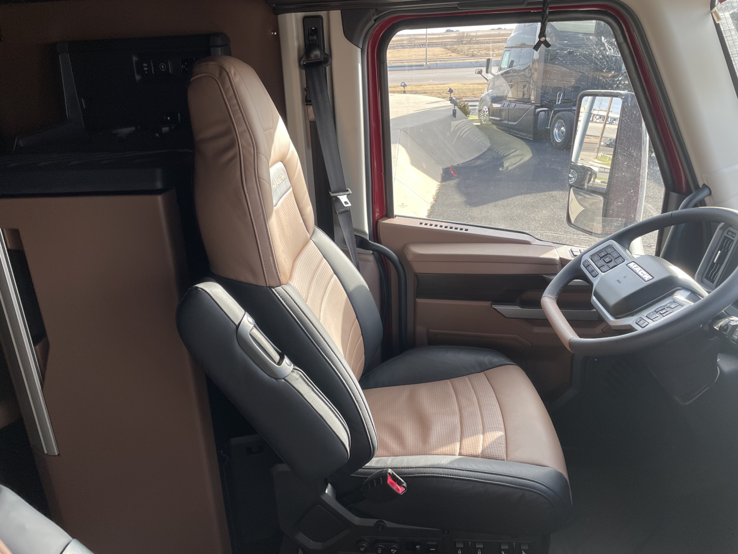 Truck cab interior with brown and black seats, steering wheel, and dashboard in view.