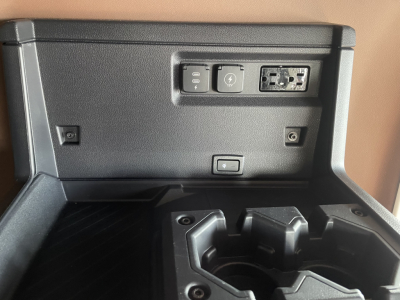 In-cab power and USB outlets panel with two USB-C/USB-A ports and auxiliary 12V socket, and center console cup holders visible.