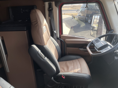 Truck cab interior with brown and black seats, steering wheel, and dashboard in view.