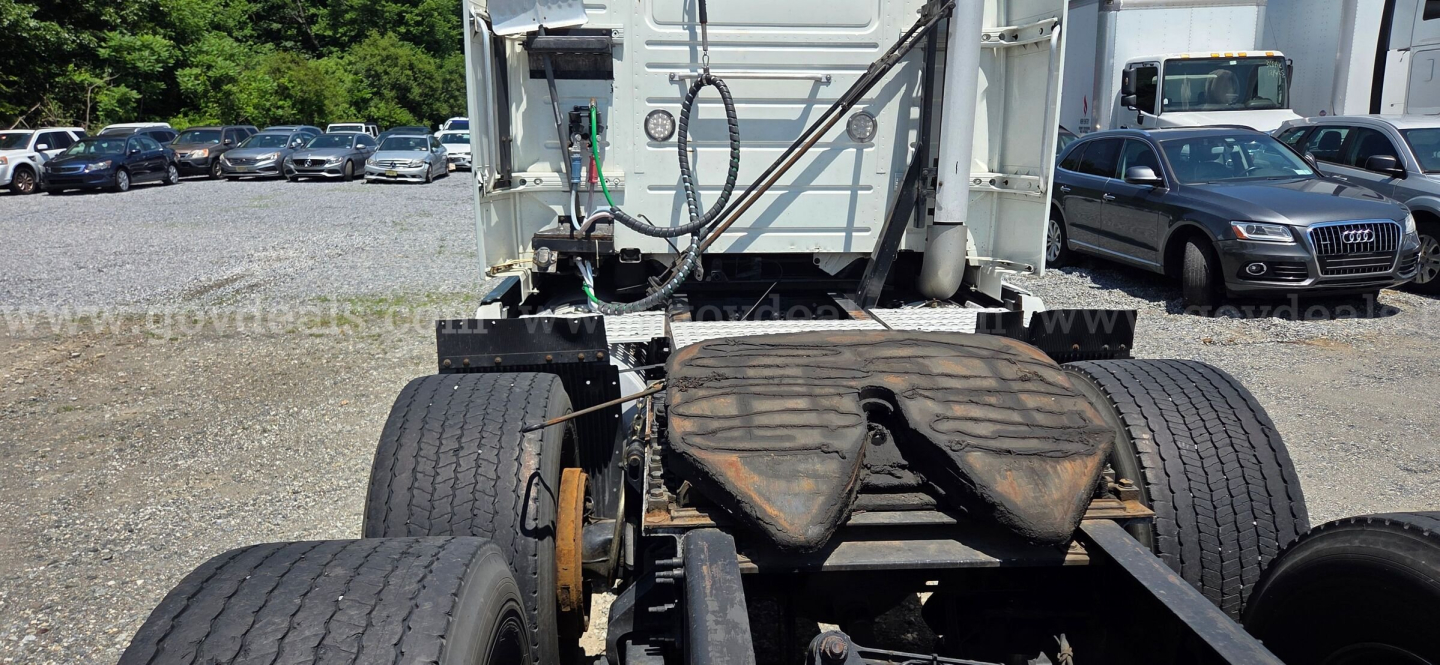 Rear view of a Volvo VNL tractor chassis showing fifth wheel and rear tires, with some rust on the step and visible hoses and components.