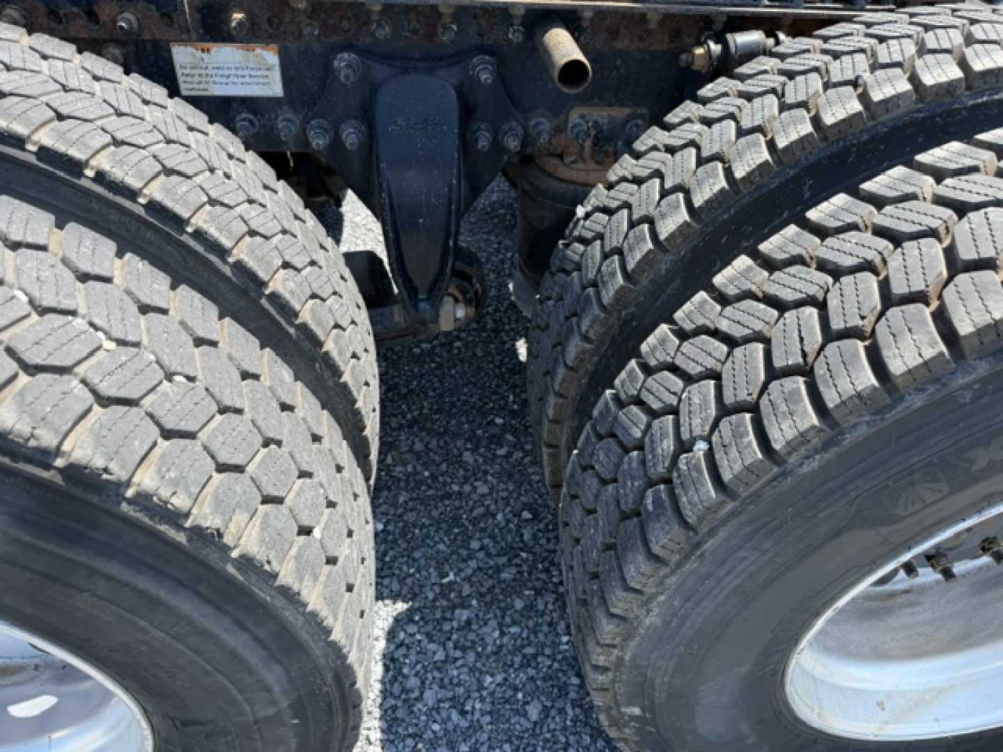 Truck rear undercarriage showing dual rear axles and tires in view with suspension components.