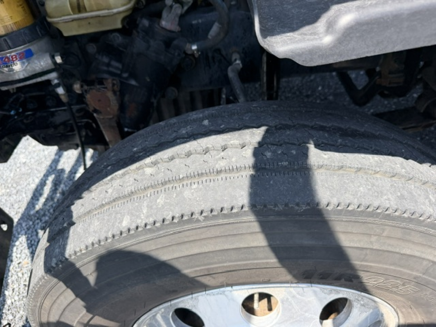 Front wheel and suspension area of a Freightliner Cascadia CA125DC undercarriage showing tire and nearby components.