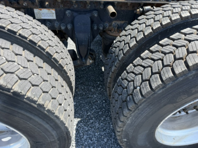 Truck rear undercarriage showing dual rear axles and tires in view with suspension components.