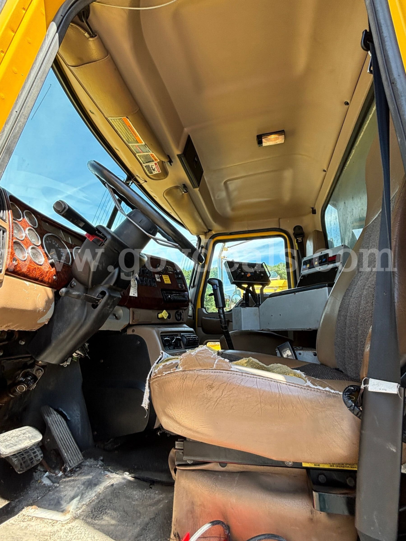 Cab interior of a 2006 Mack CV713 dump truck showing steering wheel, dashboard, driver seat, and cabin ceiling.