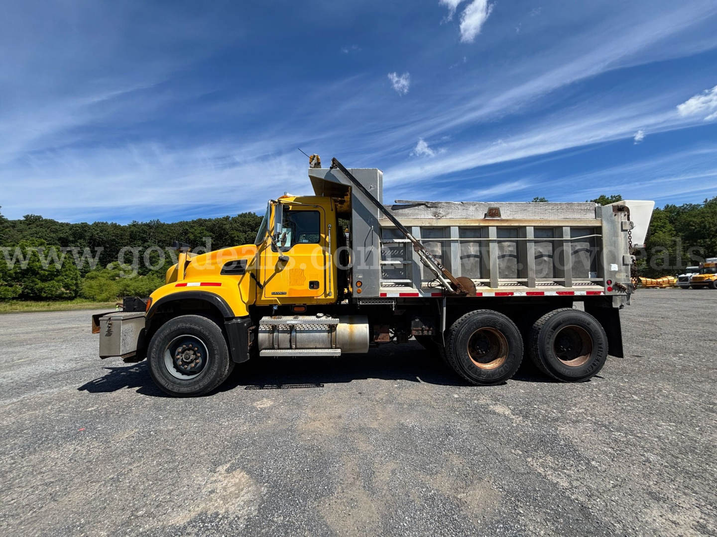 Yellow Mack CV713 dump truck side view showing dump bed and rear tires with stock number 30360