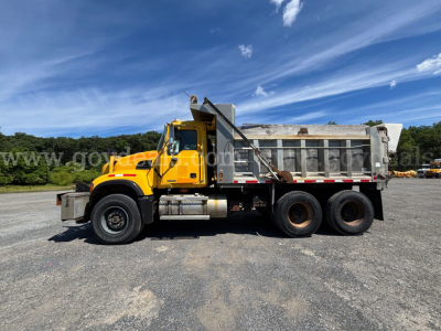 Yellow Mack CV713 dump truck side view showing dump bed and rear tires with stock number 30360