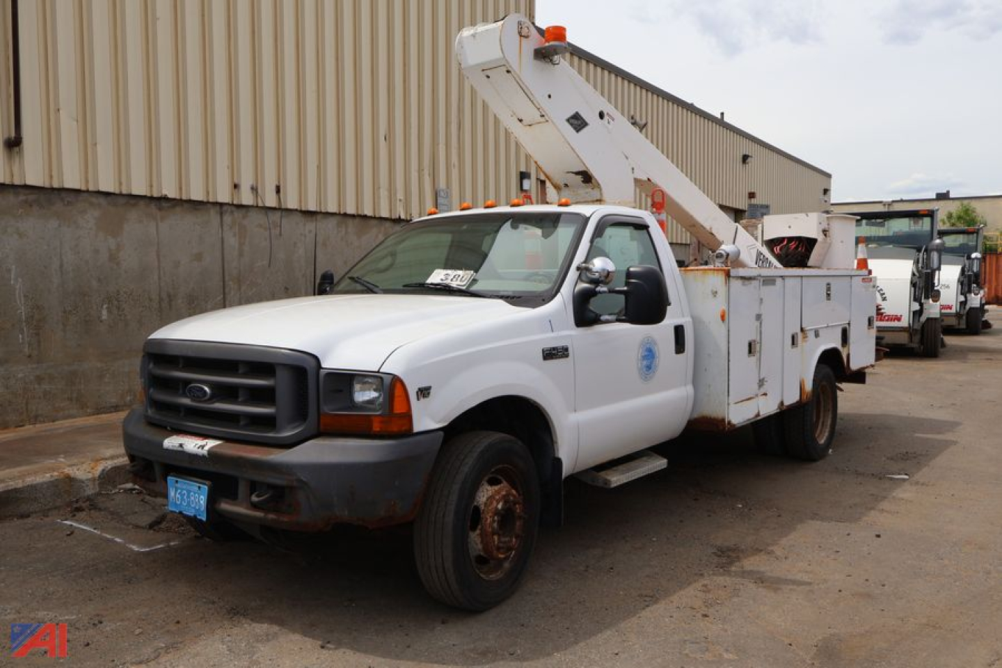 Ford F-450 Super Duty bucket truck with utility body and elevated bucket arm, white cab, in-service condition.