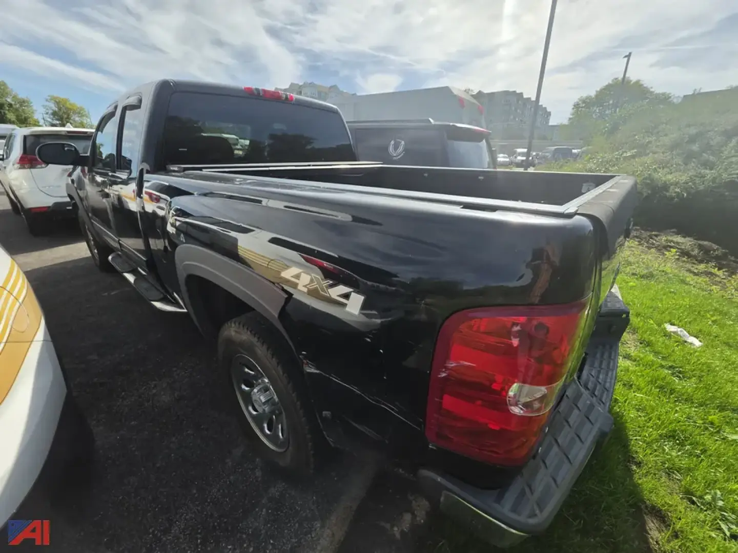 Truck bed of a black 2009 Chevrolet Silverado 1/2 Ton crew cab pickup with extended bed, rear taillight, and 4x4 badge visible; side view showing chrome wheel, tailgate area, and dirt/ground around.