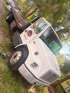 Freightliner FL80 tow truck cab front view showing white body and crew cab with logo on door.