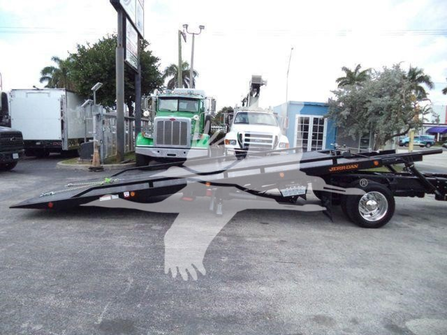 Flatbed tow truck with extended ramp in a lot, International CV image with other trucks in background.