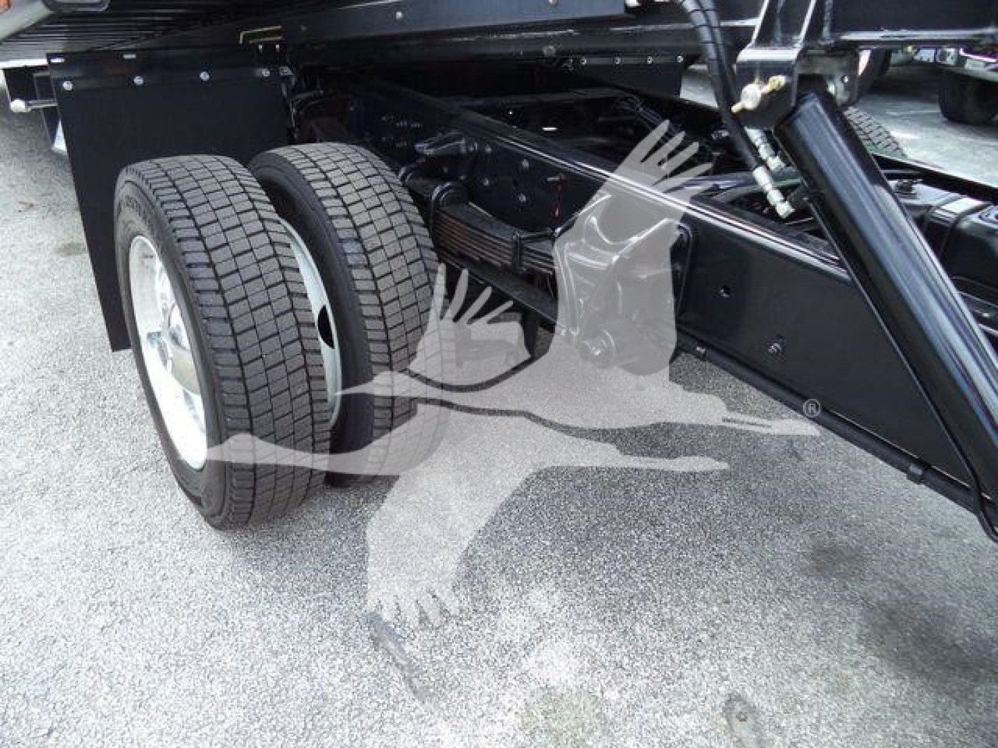 Dual rear wheels and heavy-duty suspension on a rollback tow truck chassis showing dual tires and black steel frame.