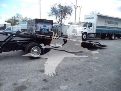 2023 International CV rollback truck and trailer in a dealership lot showing a low-loading platform with spare wheels and Ferguson-branded trucks in the background.
