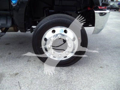 Front wheel and hub of a new 2023 International CV rollback truck showing chrome wheel with tire and undercarriage components.