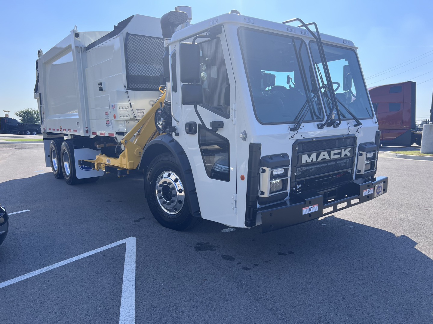 Mack LR64 front cab view with a white tractor and a dump body, showing 'MACK' logo on grille and multiple side panels.