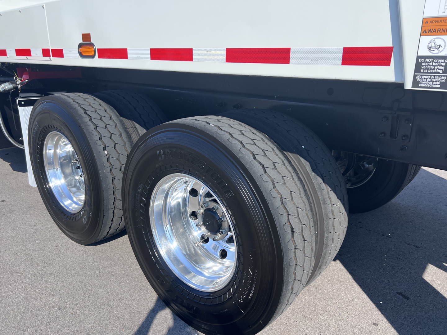 Two rear dual wheels on a Mack LR64 truck trailer showing tires, rims, and part of the undercarriage; no legible labels or text visible on the tires or nearby surfaces.