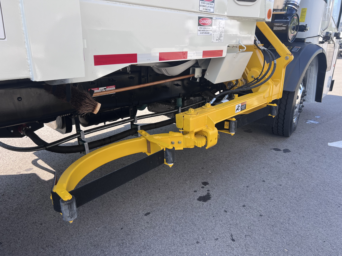 Rear view of a 2026 Mack LR64 truck with a yellow hydraulic tailgate/spotter arm extending from the chassis.
