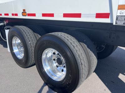 Two rear dual wheels on a Mack LR64 truck trailer showing tires, rims, and part of the undercarriage; no legible labels or text visible on the tires or nearby surfaces.