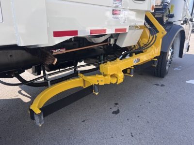 Rear view of a 2026 Mack LR64 truck with a yellow hydraulic tailgate/spotter arm extending from the chassis.