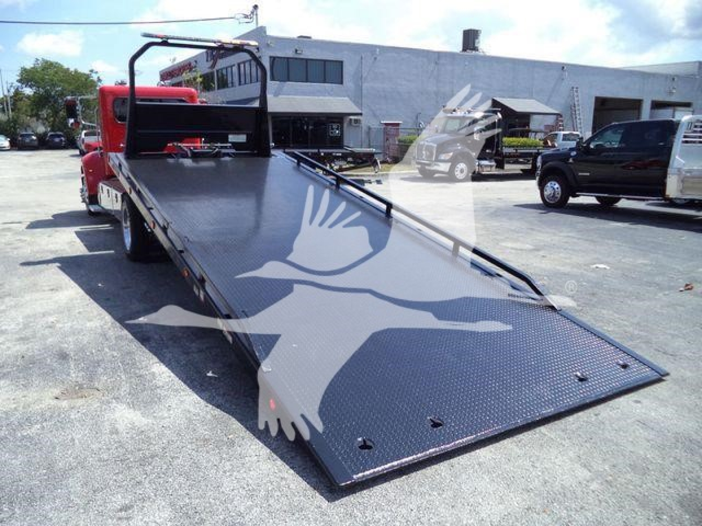 Peterbilt 337 rollback tow truck with lowered flatbed ramp, rear view shows black diamond plate surface and loading ramp extended.