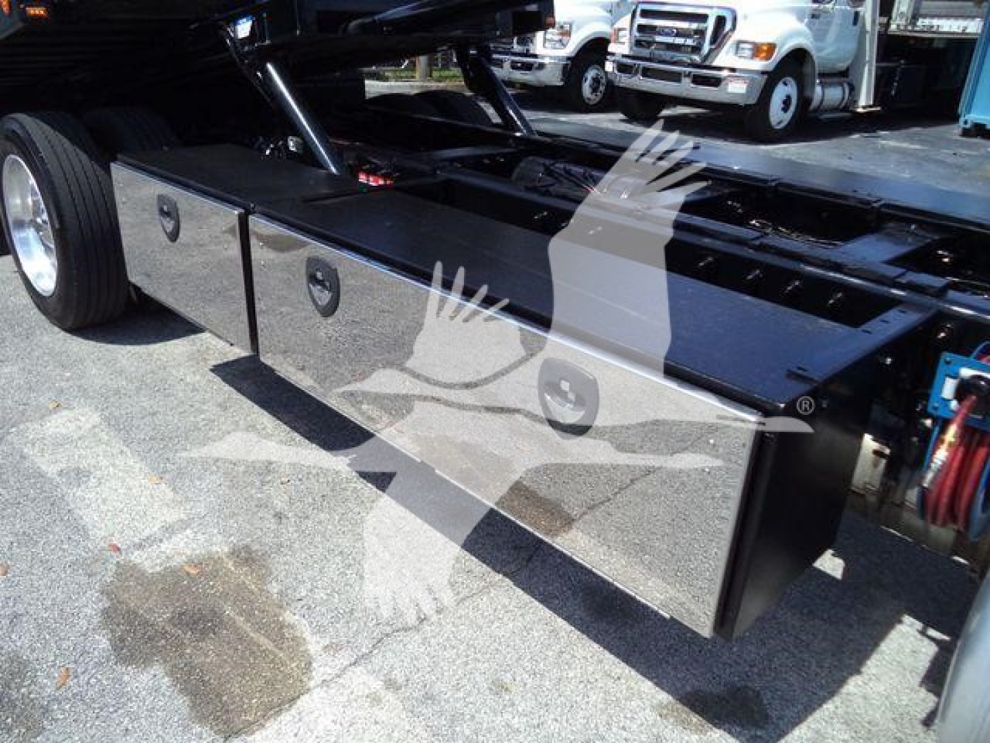 Truck chassis with large black toolbox compartments along frame of a Peterbilt 337 rollback truck. Side view shows storage boxes and rear wheel area.