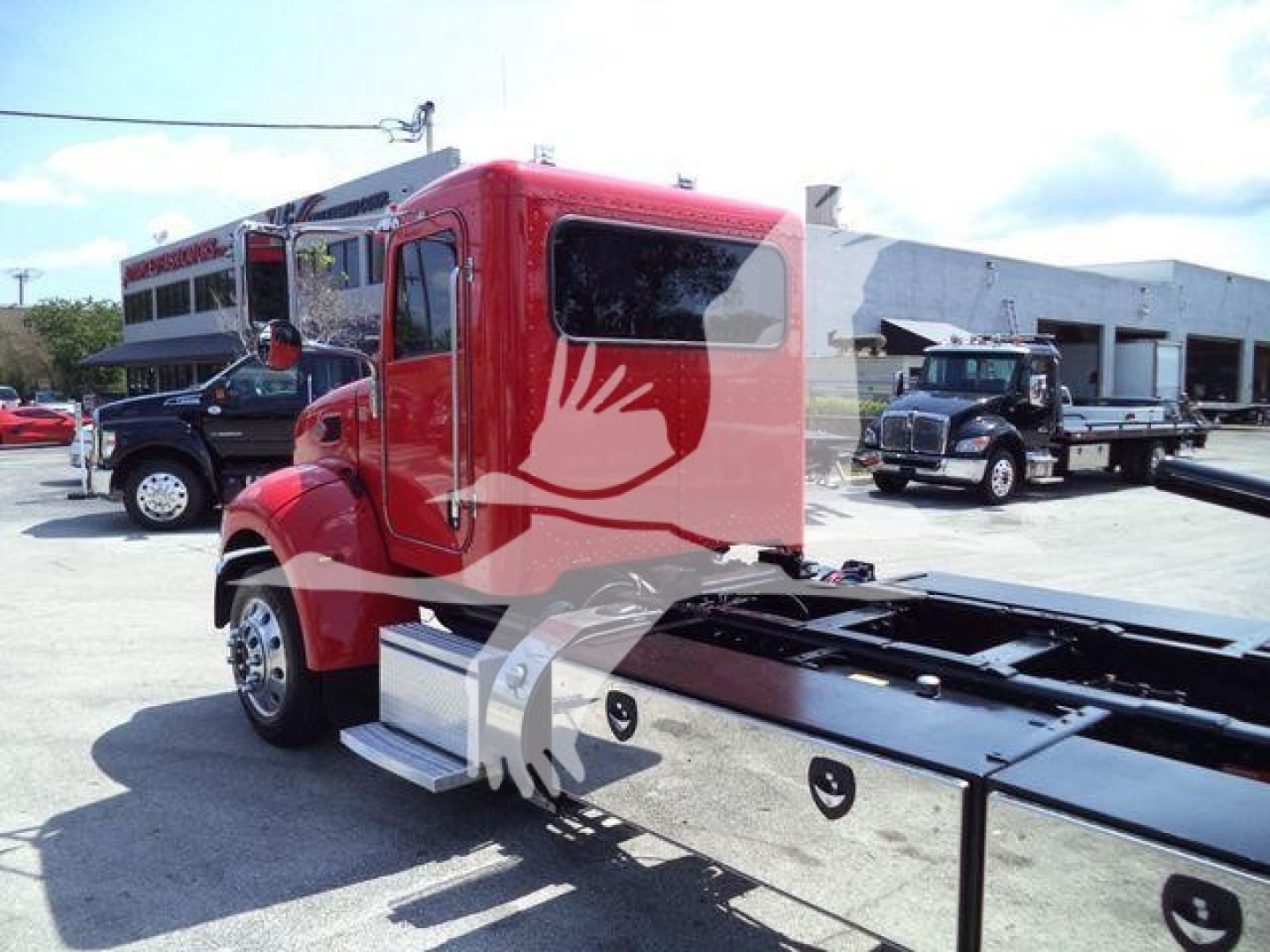 Peterbilt 337 rollback truck cab and chassis shown from side/front angle in red color with flatbed rear and other trucks in background.