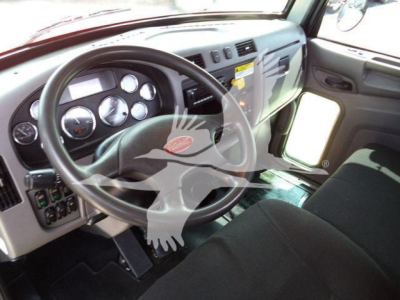 Peterbilt 337 cab interior showing steering wheel, dashboard gauges, and driver seat in a rollback truck.