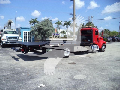 Peterbilt 337 tow truck with rollback bed, red cab, parked in lot; stock number T21864 visible