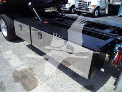 Truck chassis with large black toolbox compartments along frame of a Peterbilt 337 rollback truck. Side view shows storage boxes and rear wheel area.