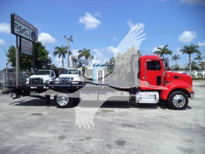 Peterbilt 337 rollback truck with bright red cab and flatbed, side view.