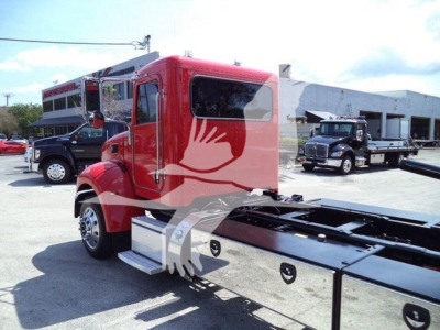 Peterbilt 337 rollback truck cab and chassis shown from side/front angle in red color with flatbed rear and other trucks in background.