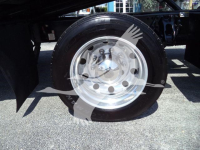 Truck wheel and rim from a Peterbilt 337, showing a shiny polished steel wheel with multiple circular holes and a black tire.