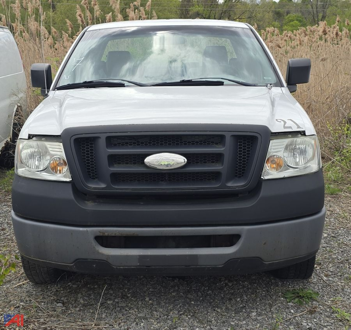 Front view of a white 2008 Ford F-150 XL pickup truck with black grille, bumper, and side mirrors on a gravel lot.