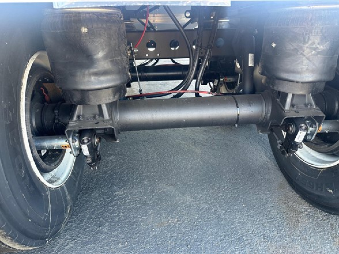 Trailer underside showing suspension beam and axles of a 2026 Timpte Super Hopper with twin air springs and solid axle connecters.