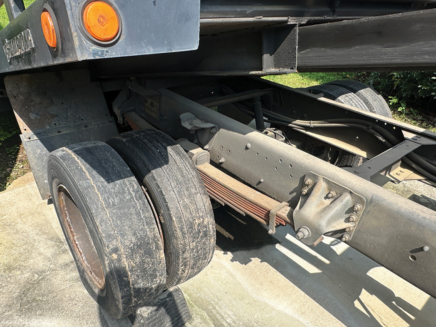 Truck chassis and dual rear tires of a 1999 Chevrolet 6500 rollback truck showing the leaf springs and frame.