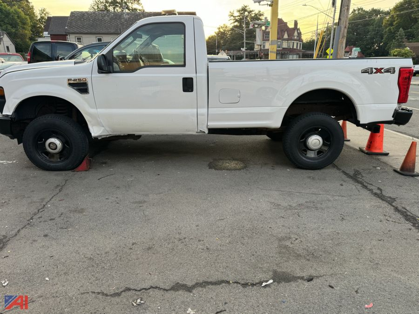 Side view of a white 2008 Ford F-250 Super Duty pickup truck with single cab, long bed, 4x4 badge, and dual rear wheels parked on pavement with orange cones nearby.