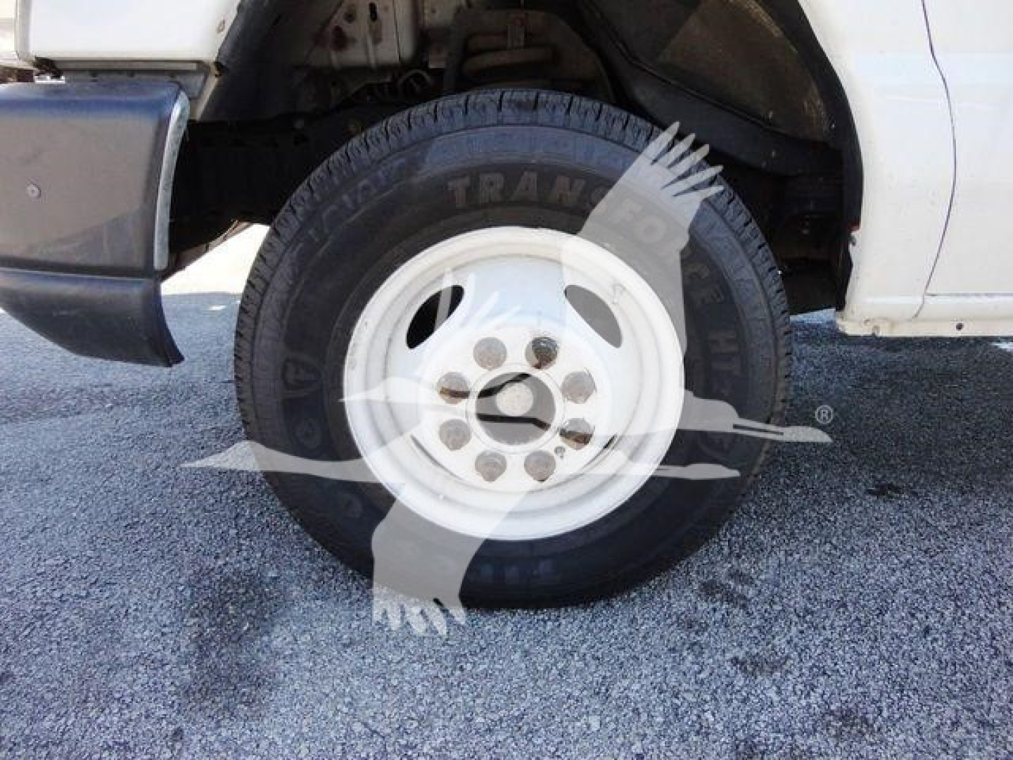 Truck front wheel and fender of a 2011 Ford E450 with a white wheel rim and black tire showing partial branding.
