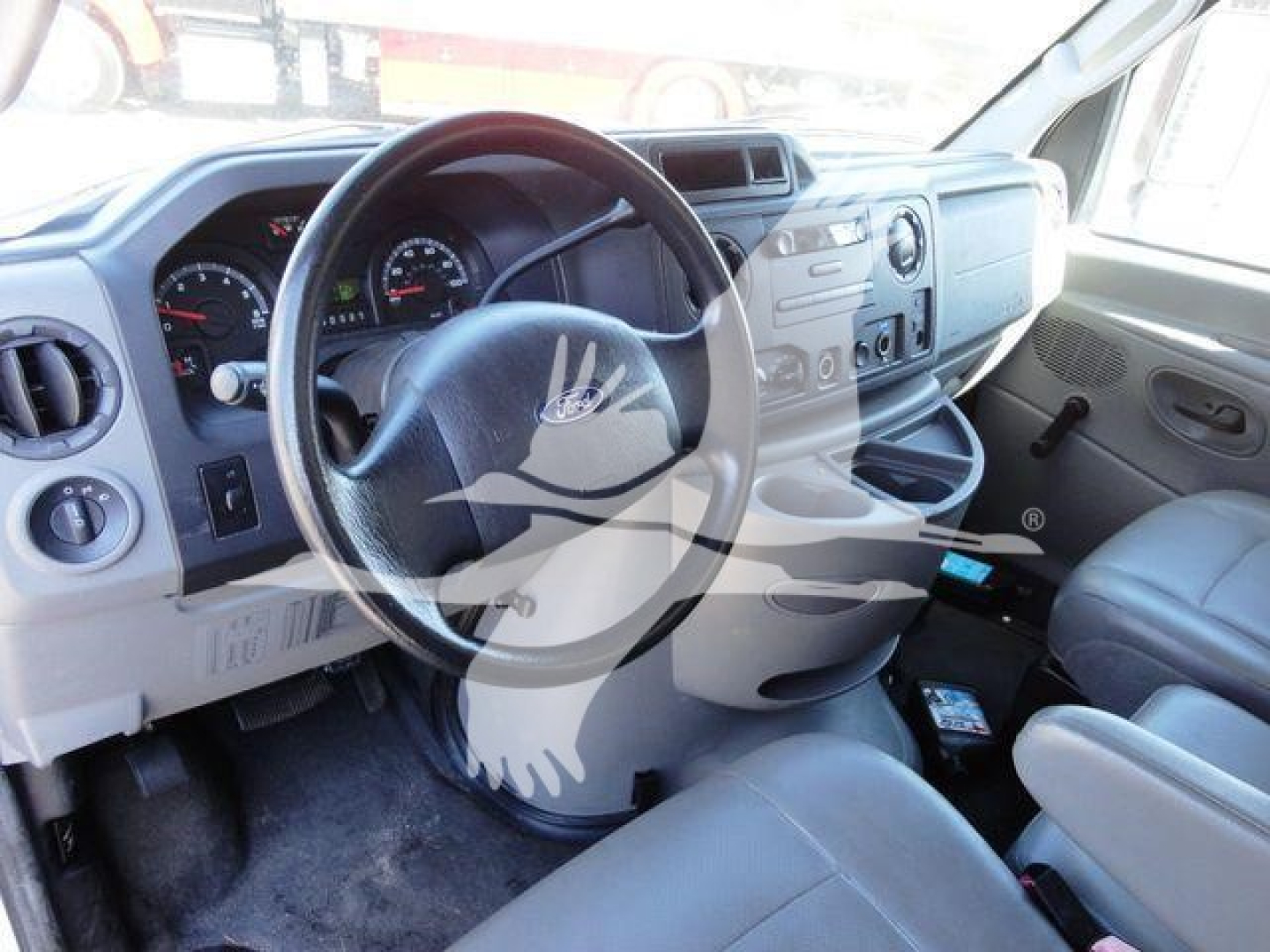 Ford E-Series van cabin showing steering wheel, dashboard gauges, and front seats with center console area visible.