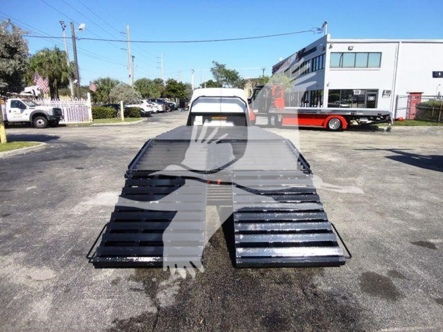 Flatbed tow truck bed with ramps and tailgate for Ford E450, rear view showing metal platform and ramps, used condition.